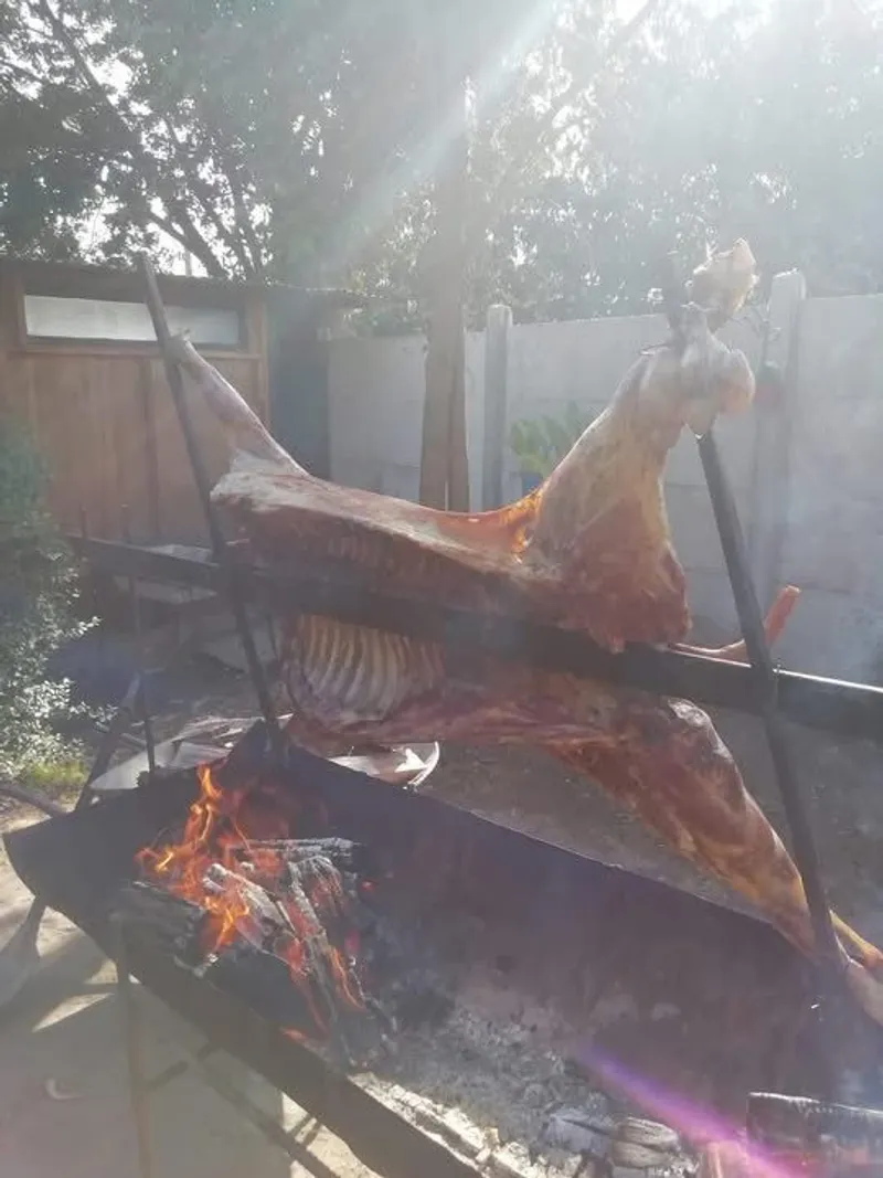 Cordero al palo asándose con sol a contraluz