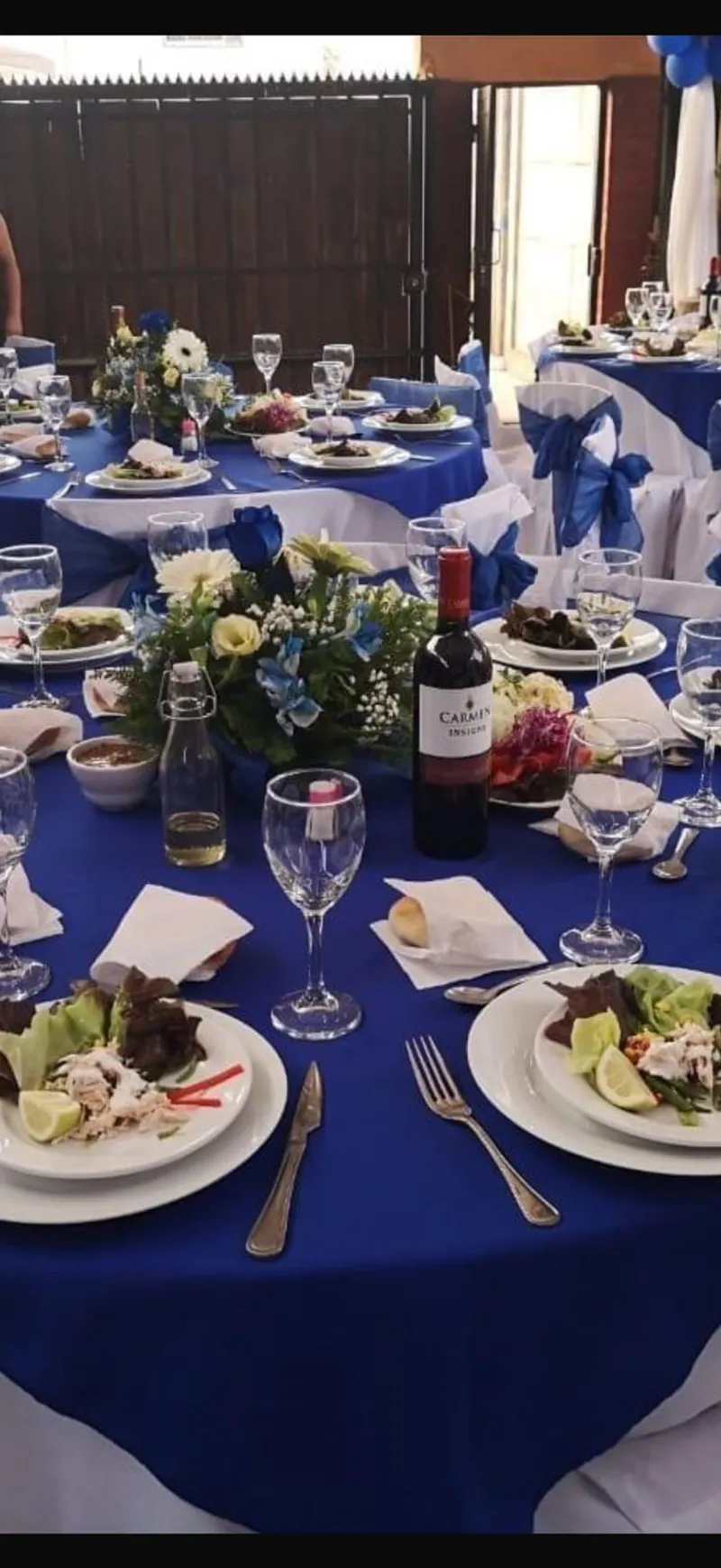 Mesa decorada con mantel azul, vino y entradas