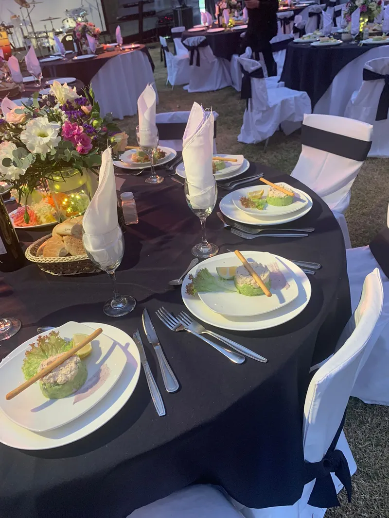 Mesa elegante con mantel negro y centro de flores